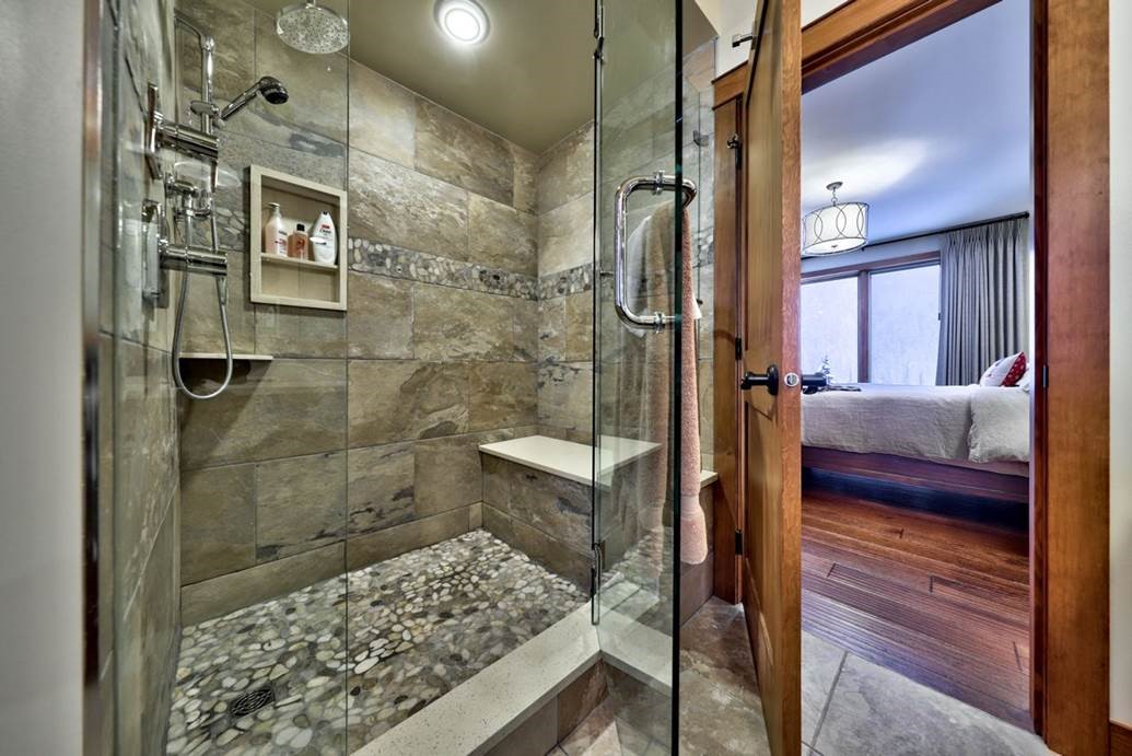 Modern shower with glass walls and stone accents, showcasing stylish panel upgrades