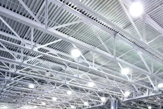 Bright overhead lights illuminate a complex, industrial ceiling structure