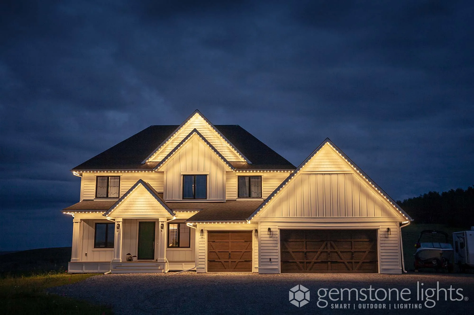 A beautifully illuminated house shines against a dark, cloudy sky