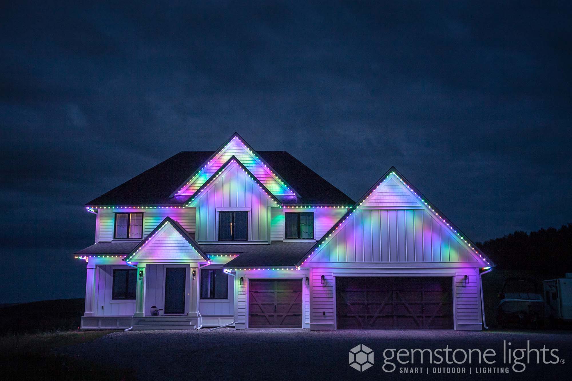 A house is illuminated with vibrant, colorful lights against a dark, cloudy sky