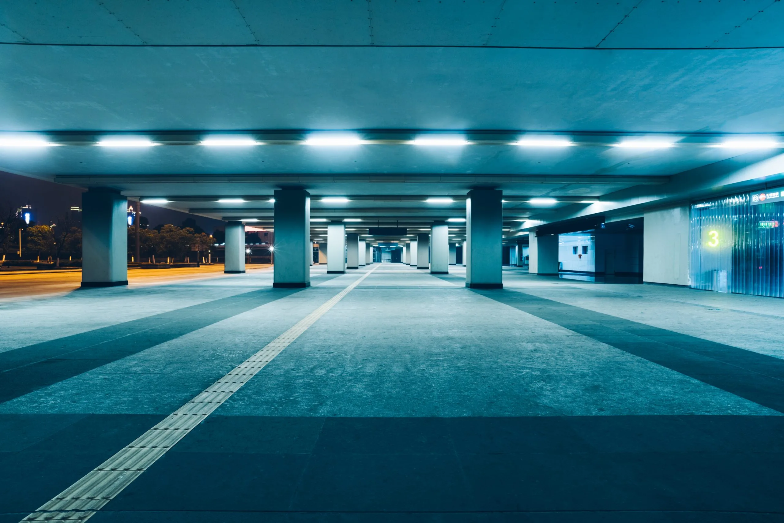 A dimly lit urban space with wide columns and polished floors under bright lights