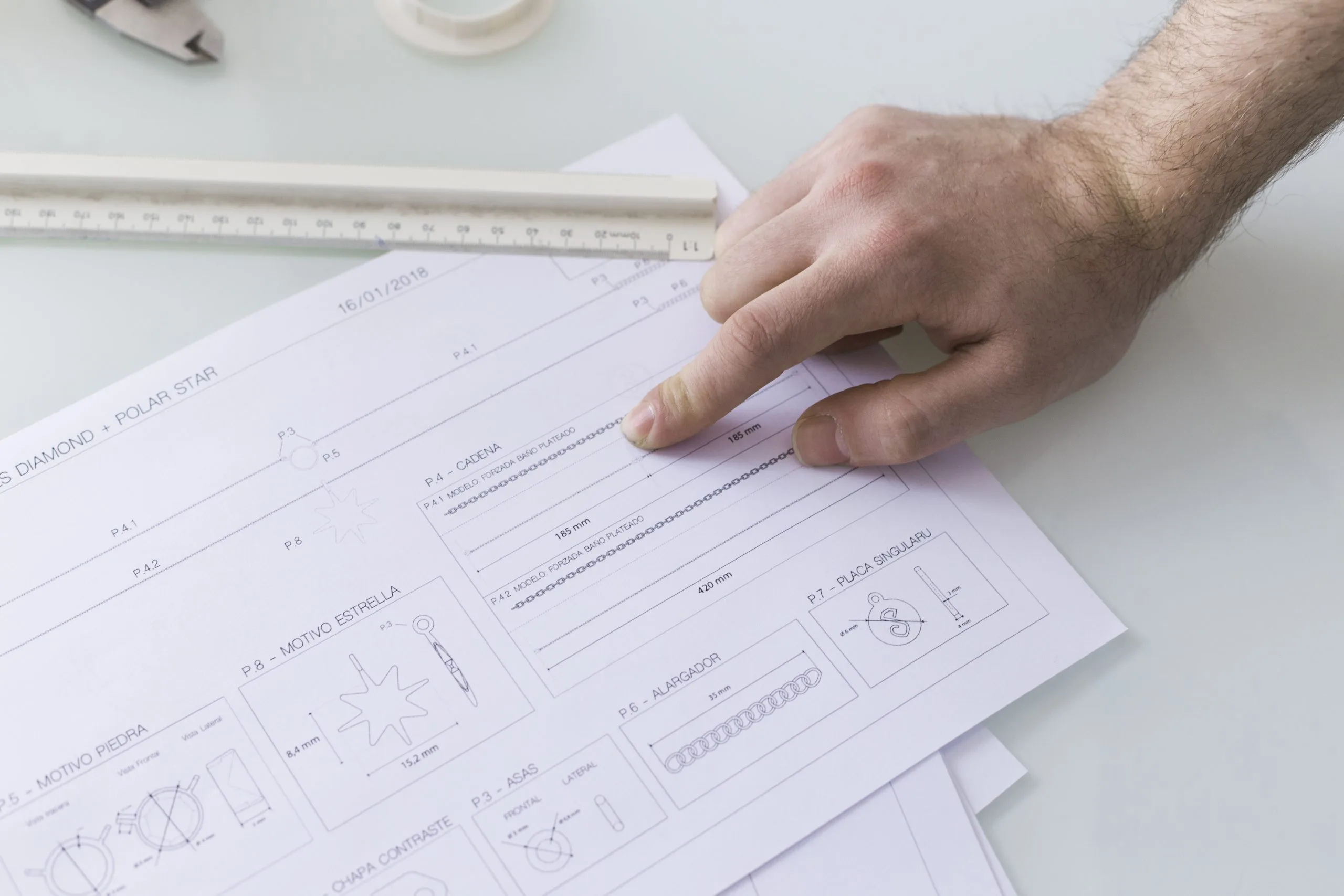 A hand points to a section on a document, surrounded by drawing tools