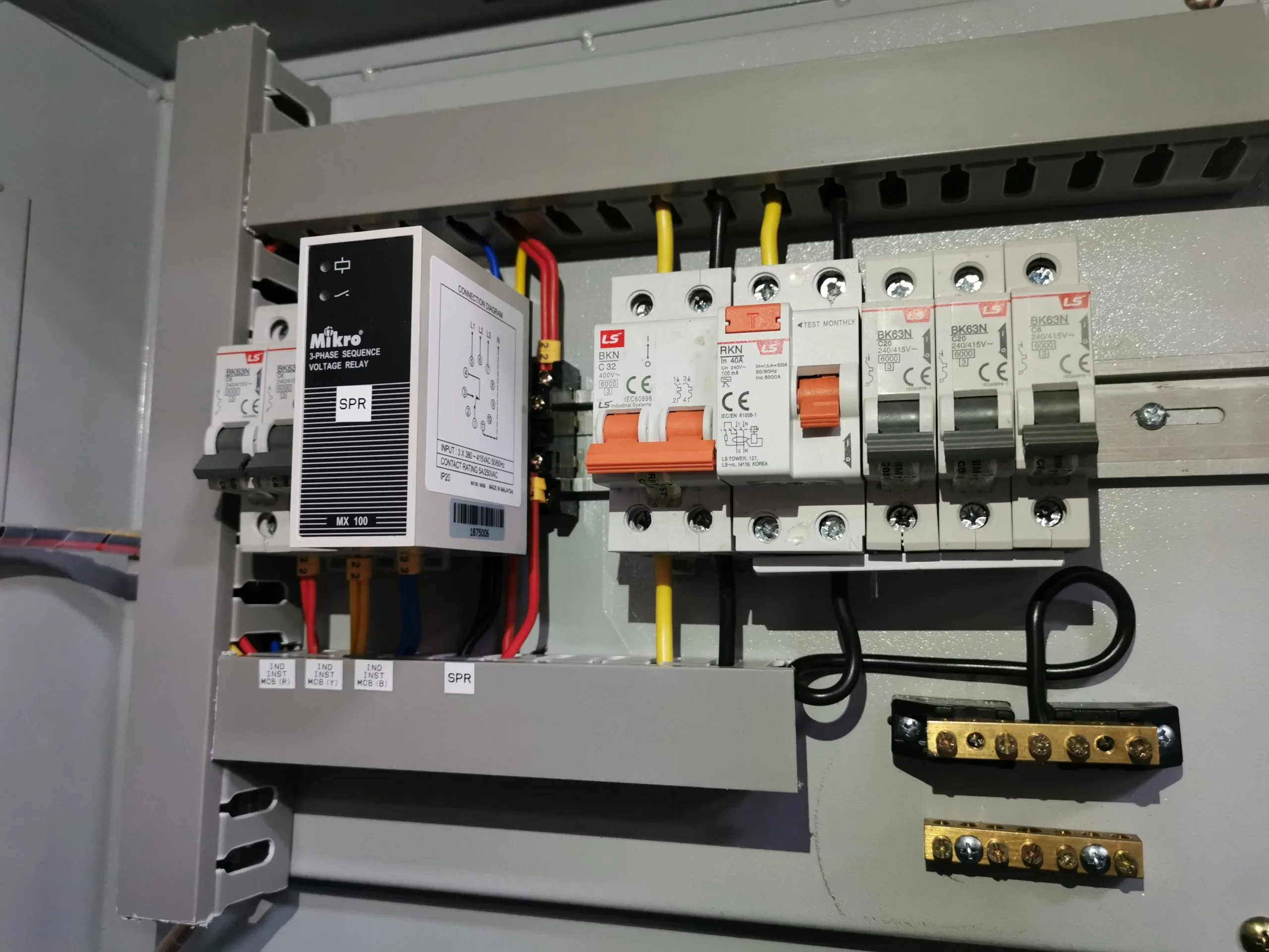 A panel displays various electrical components and circuit breakers connected with colorful wires