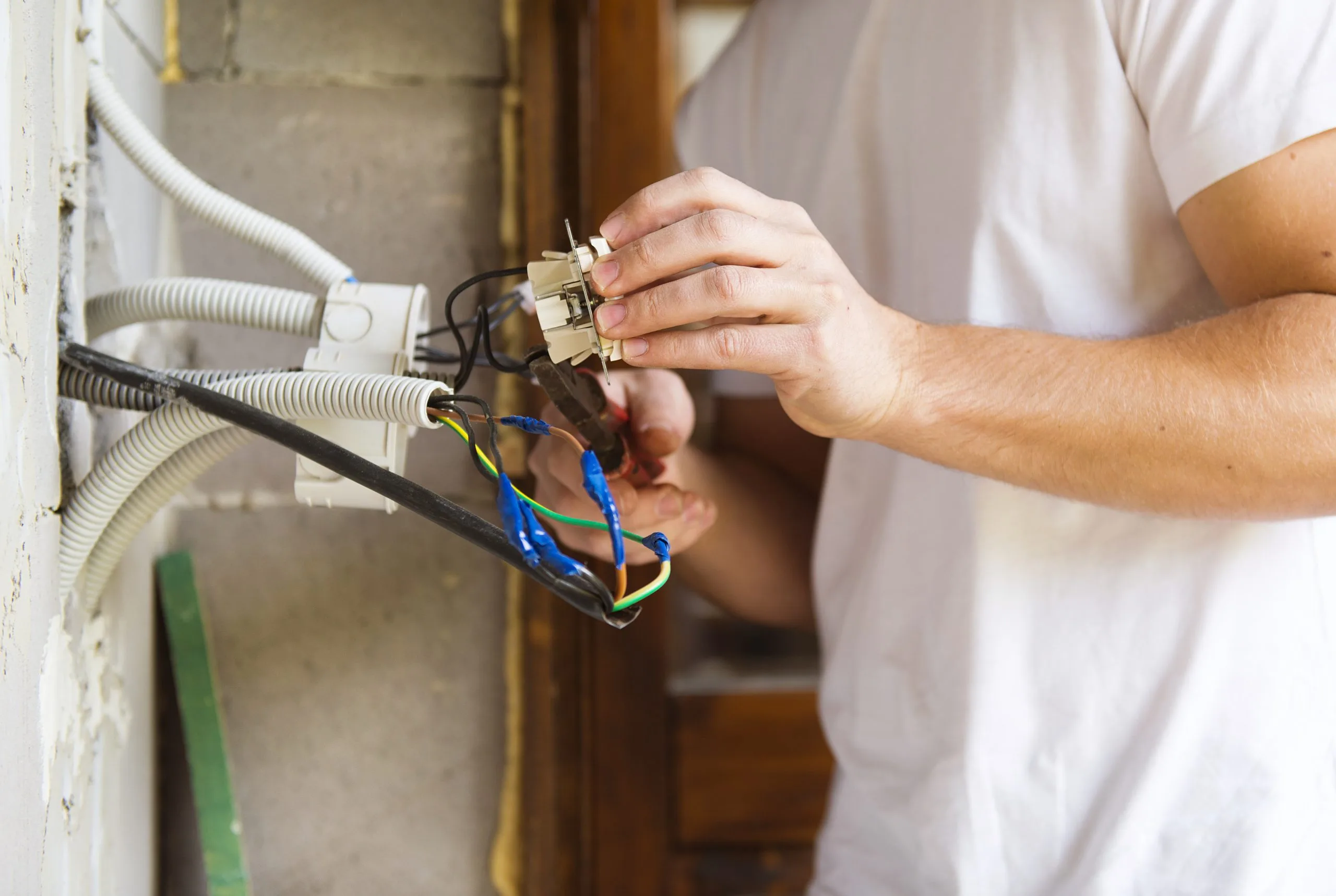 A person is connecting wires to an electrical socket