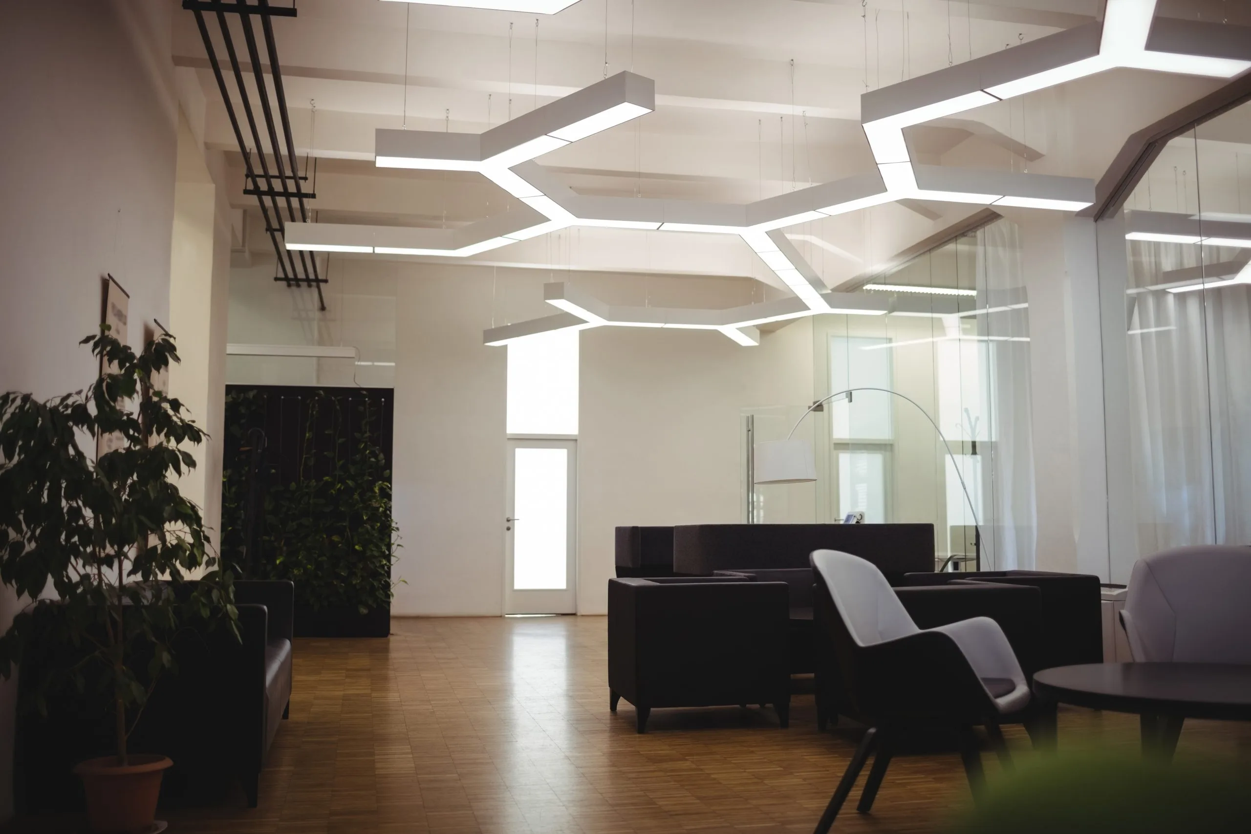 A modern, spacious room features unique geometric lighting and minimalist furniture